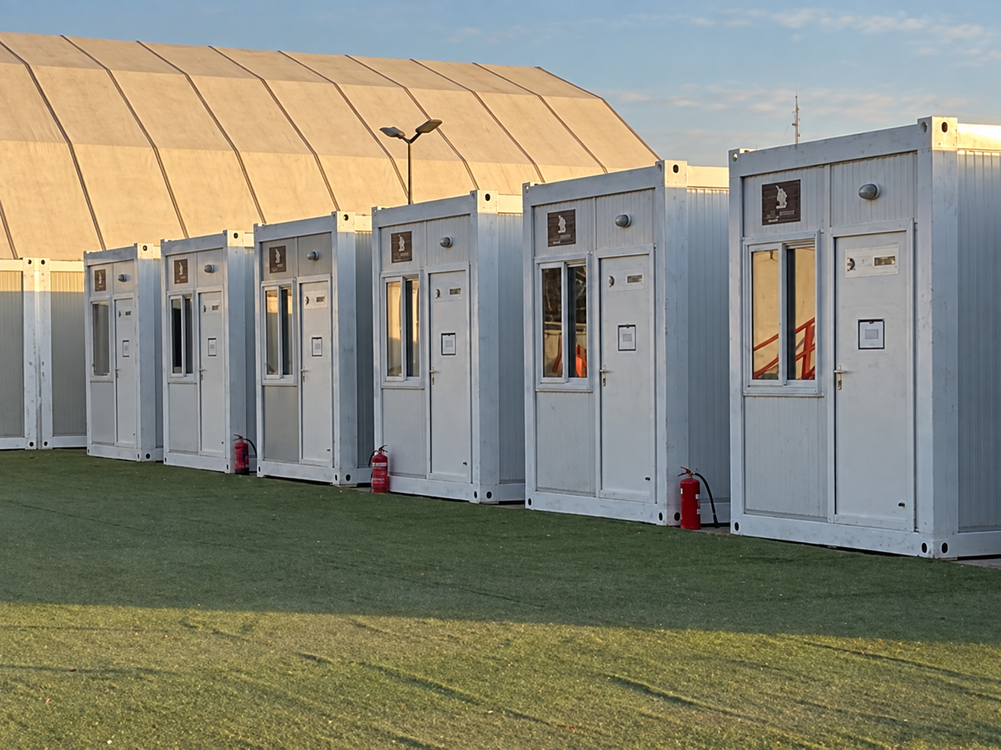 Fronts of white flat-pack cabins on the festival site