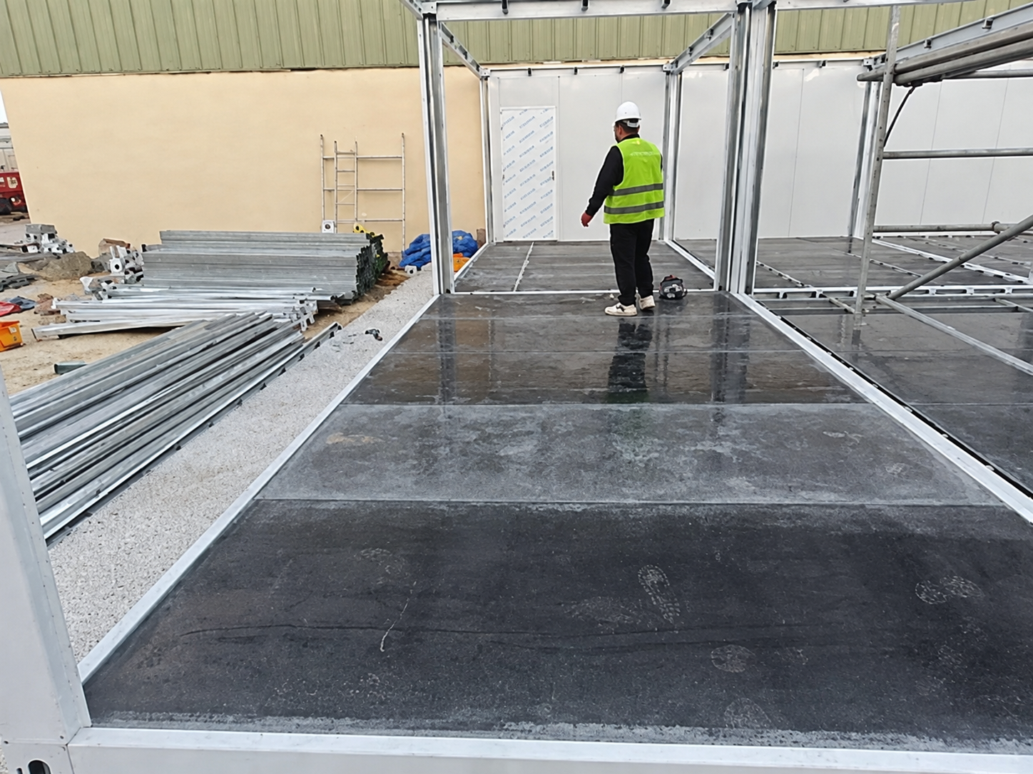 Worker inspecting a modular office floor deck and frame during site assembly