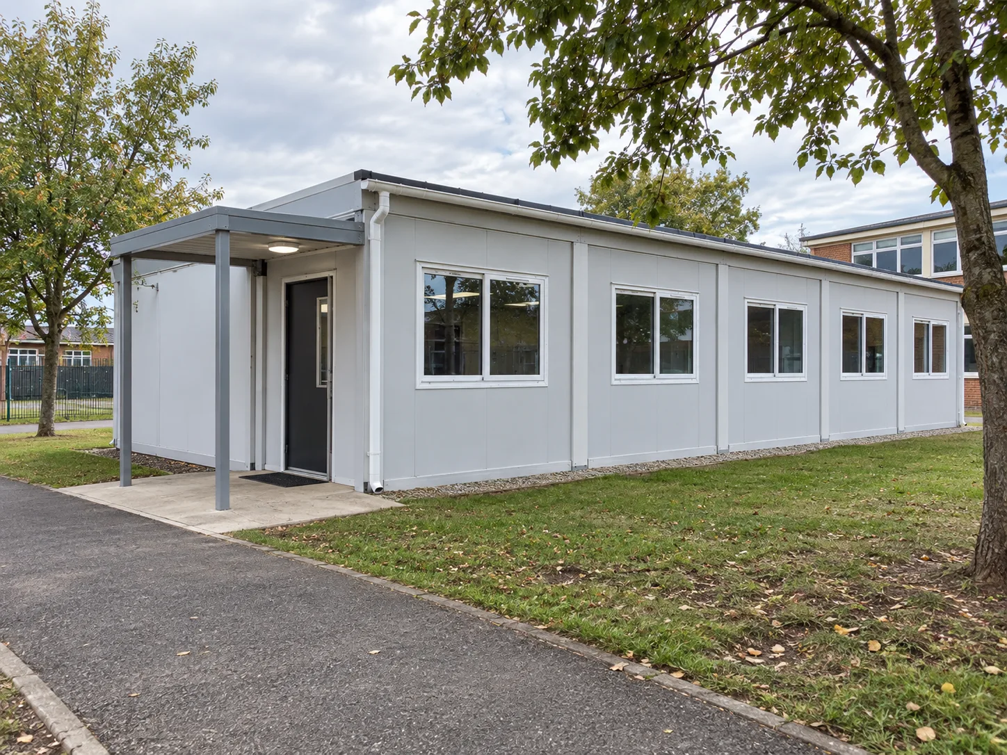 Standalone modular classroom with a covered entrance and side windows