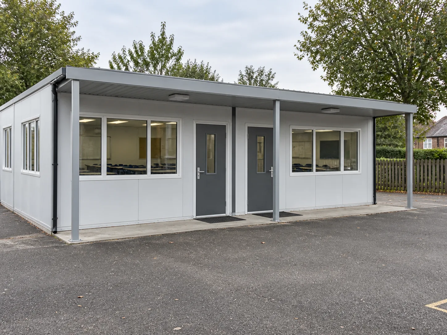 Paired modular classrooms with separate doors beneath a shared canopy