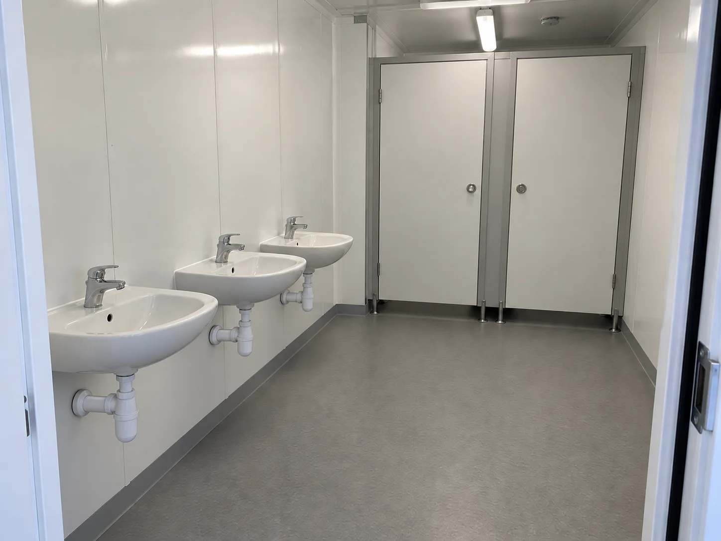Handwashing basins beside modular school toilet cubicles