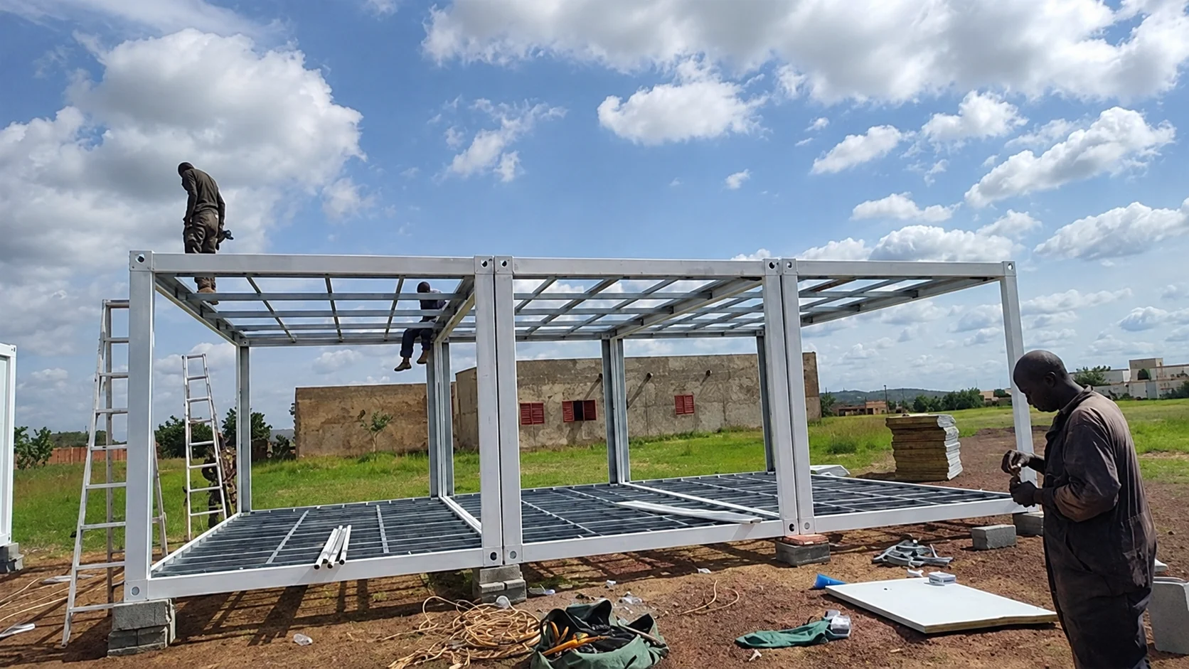 Workers fitting roof framing to a white modular structure
