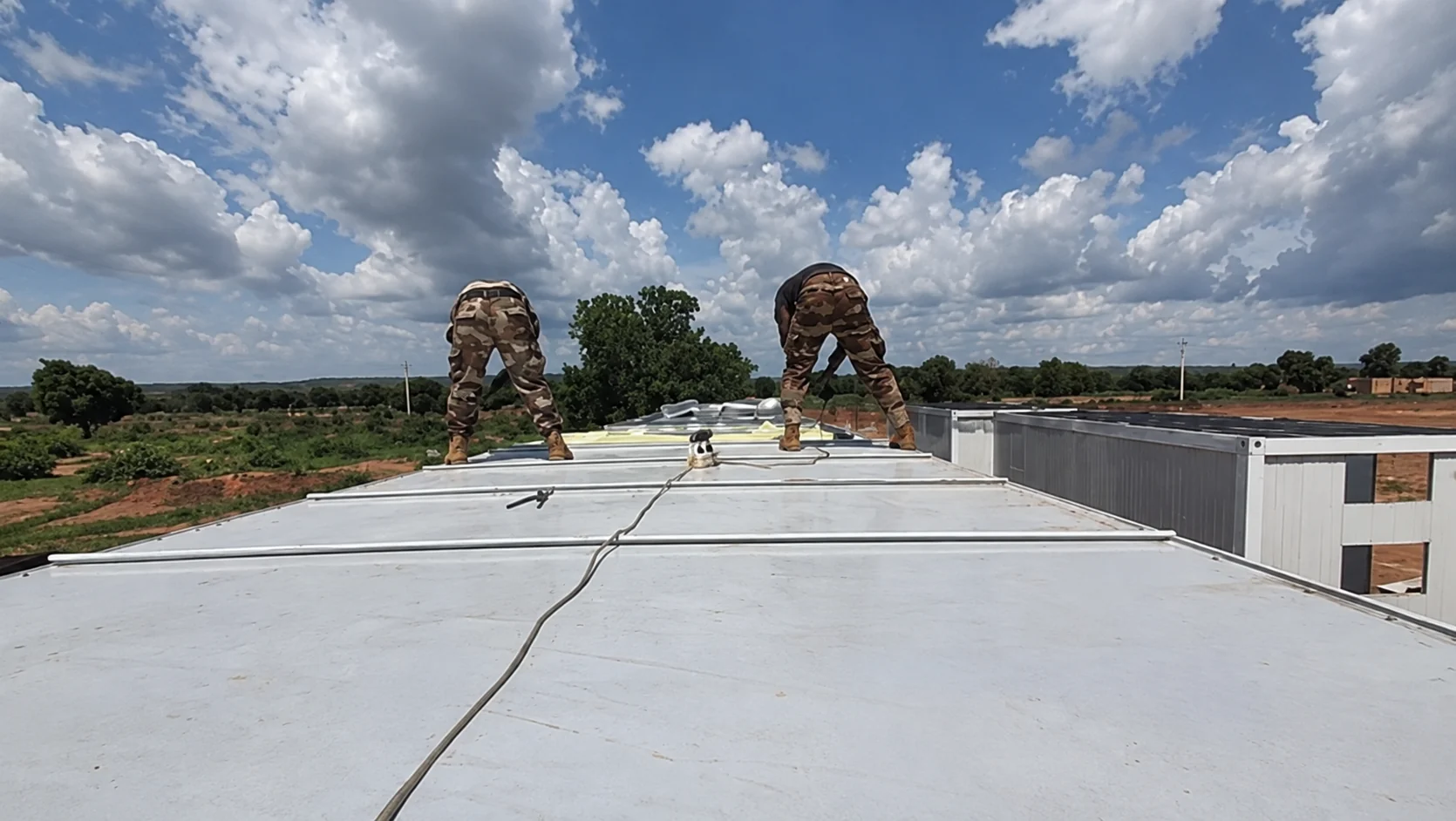 Workers fitting roof panels atop a row of modular cabins