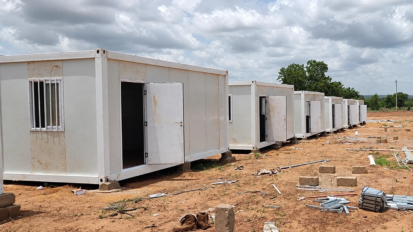 Row of white accommodation cabins along an unpaved site track