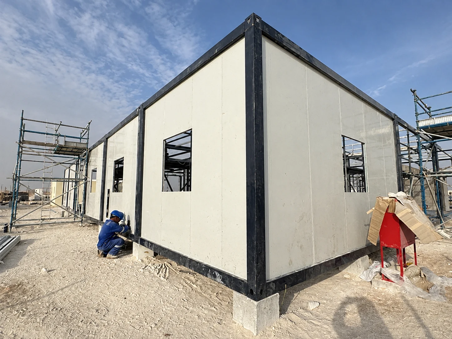 White wall panels fitted to a black steel modular frame on site