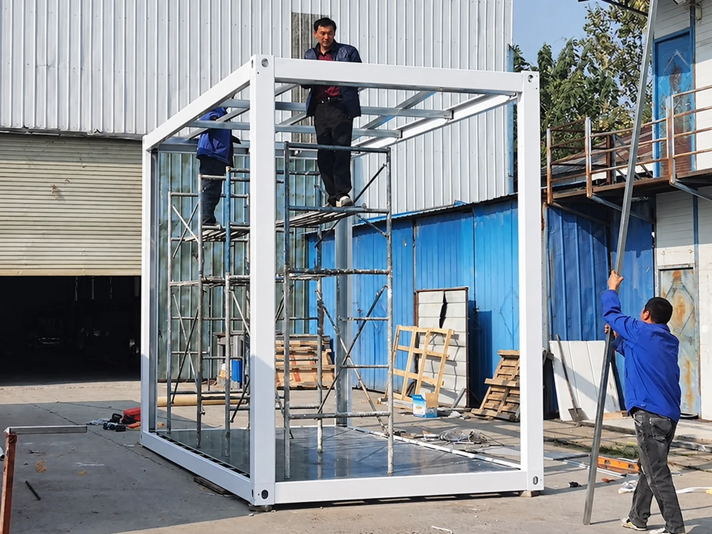 Workers aligning the upper frame of a white service module during preassembly