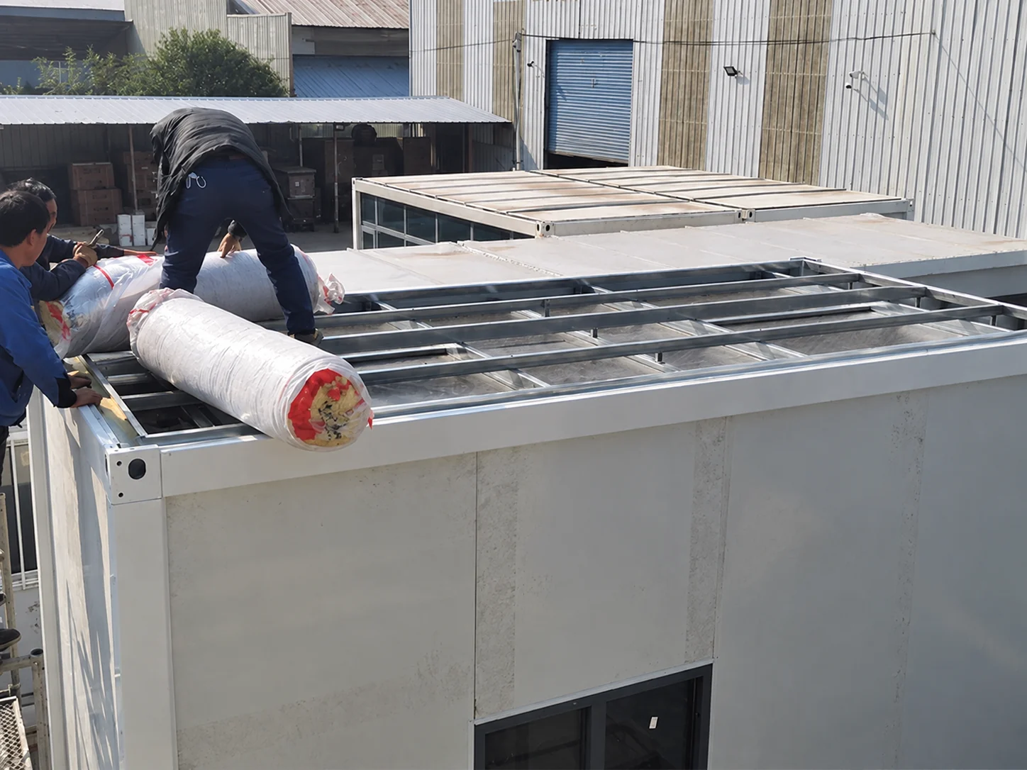 Workers placing a roll of material on the roof of the service module