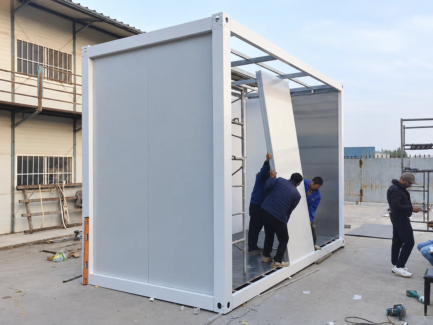 Workers positioning a wall panel inside the white service module frame