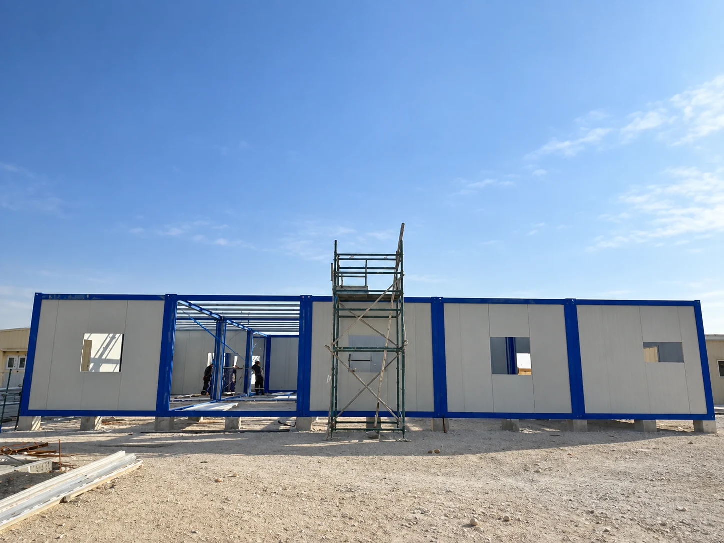 Row of blue and white modular bays with a scaffold during construction