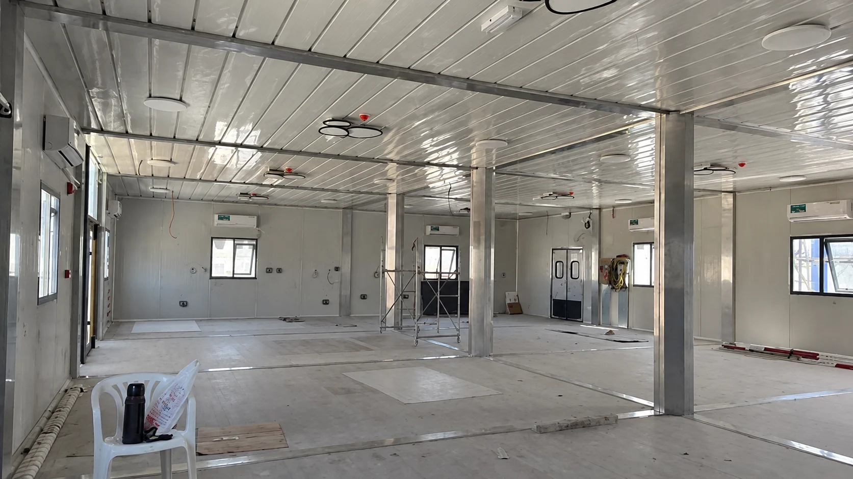 Large white-paneled room with columns during kitchen and dining fit-out