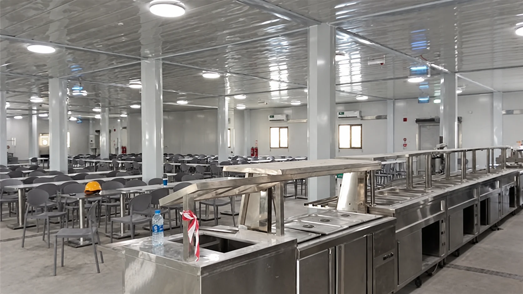Rows of dining tables and a long stainless serving counter