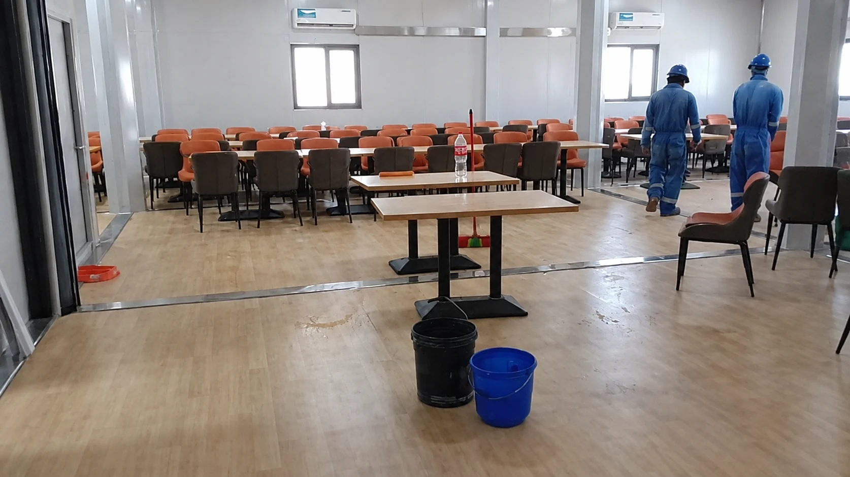 Dining tables being arranged in the modular hall with workers present