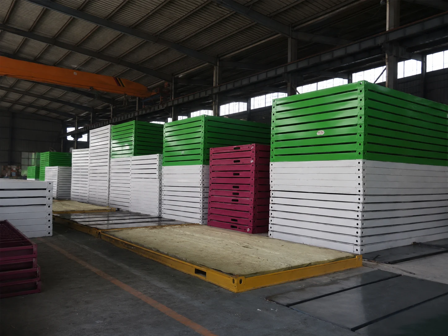 Stacks of painted modular building frames in a factory workshop