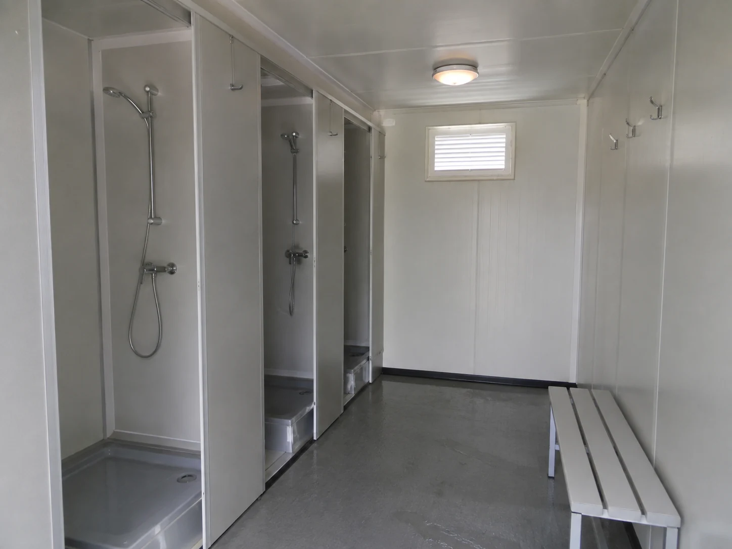 Illustrative modular shower block with partitioned bays and a changing aisle
