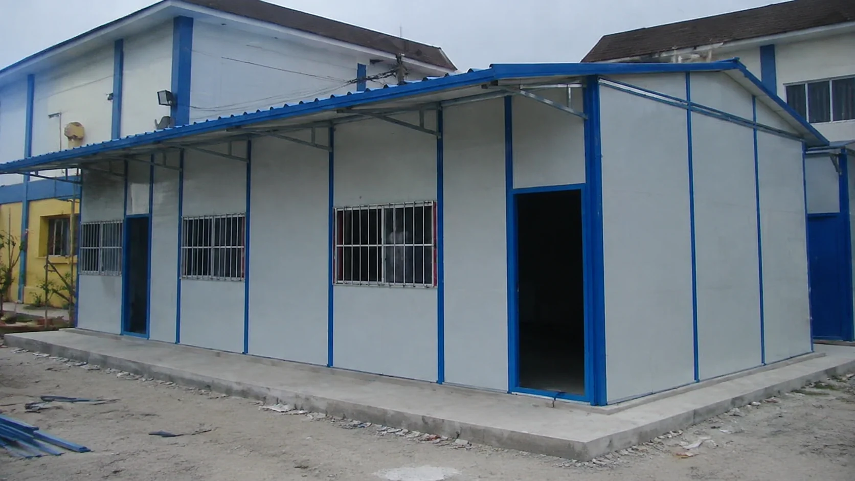 Blue-and-white prefab site office with windows and a covered entrance