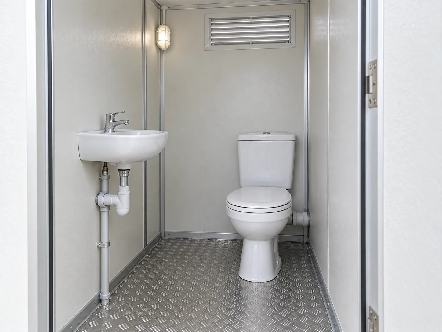 Illustrative portable toilet interior with a seated WC, compact basin and ventilation opening