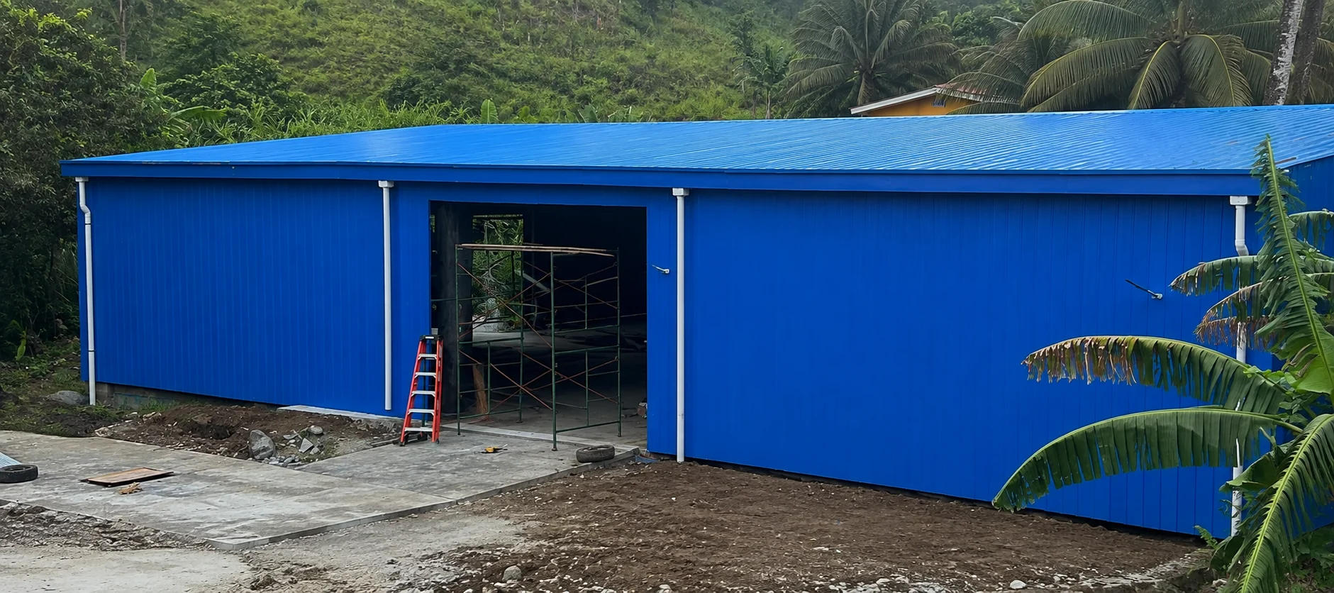 Blue prefab steel workshop with a wide entrance