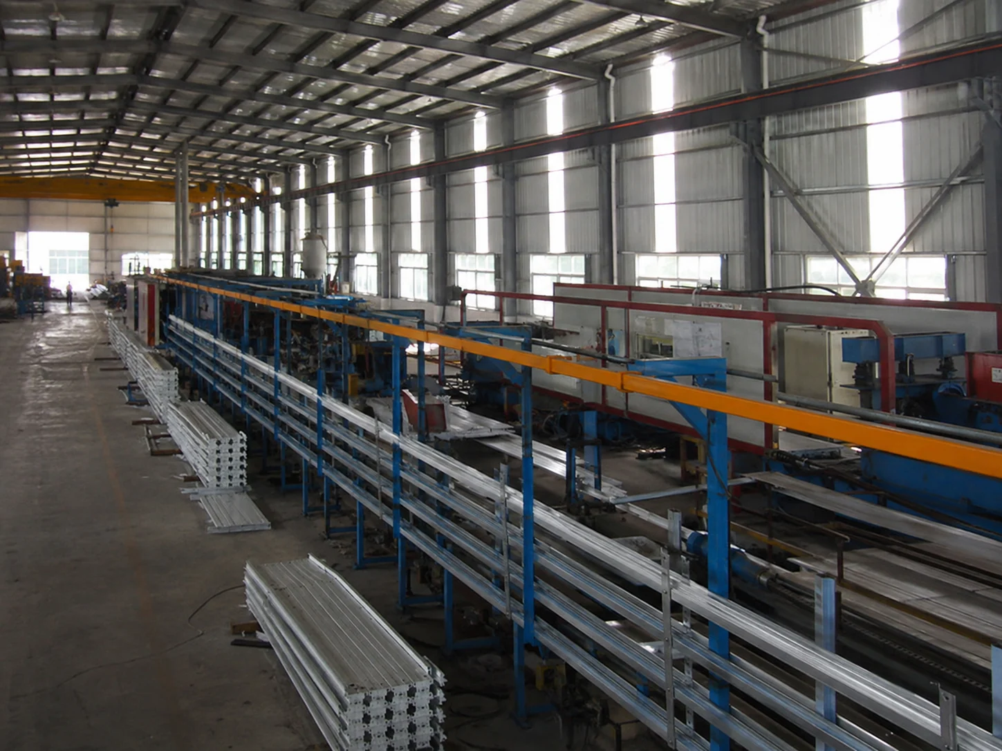 Factory production line with stacked steel profiles and processing equipment