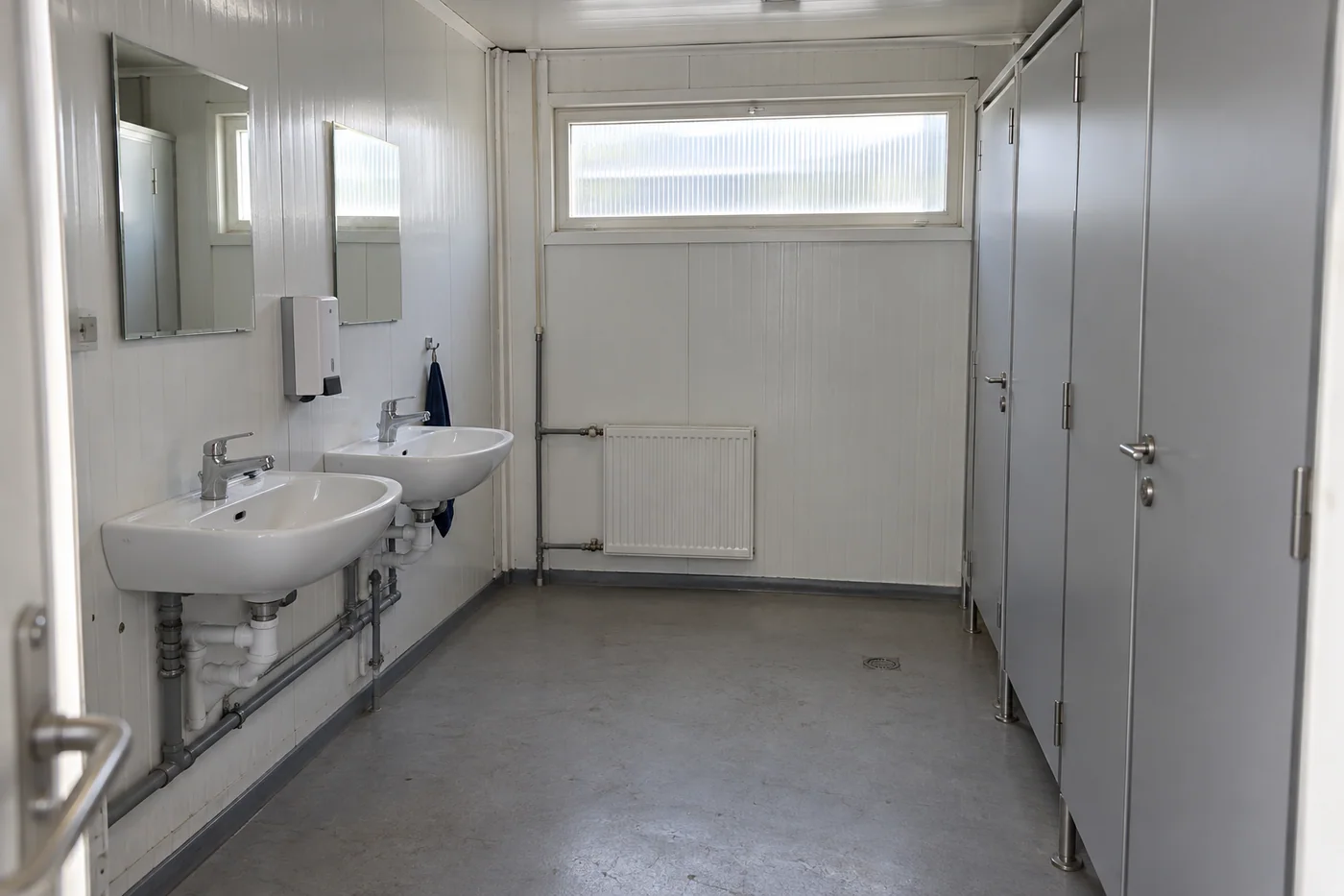 Shared modular washroom with handwashing basins and separate toilet cubicles