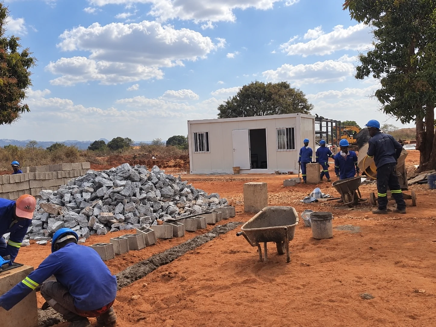 Workers preparing a foundation edge beside a white modular building