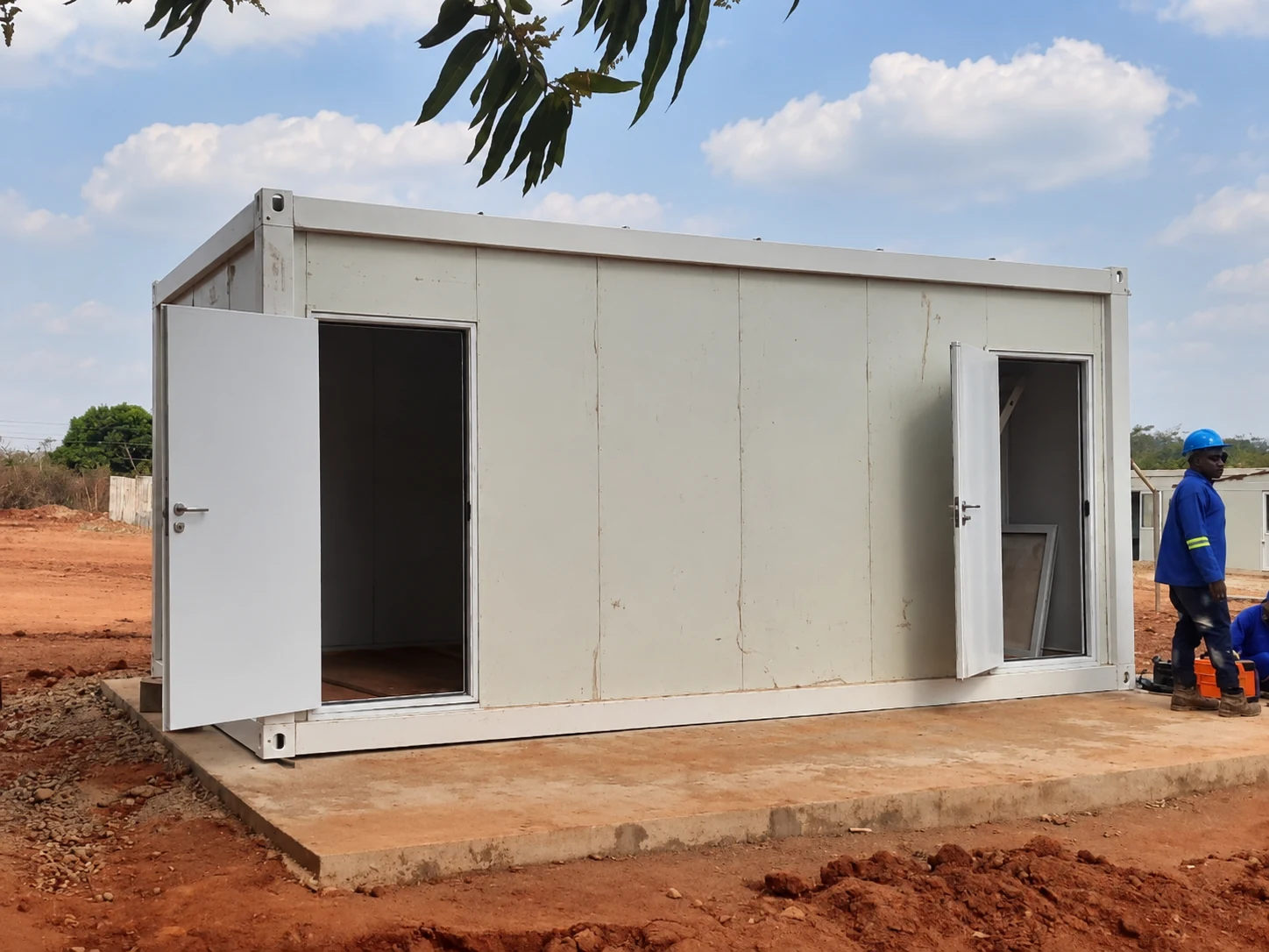 White modular room with open doorways and site workers nearby