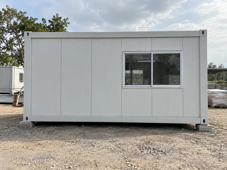 Reference white modular cabin with a sliding window on gravel