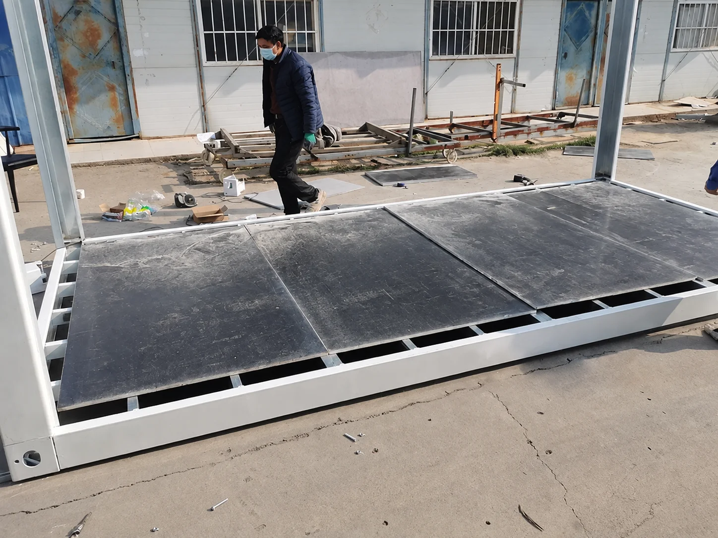 Reference worker fitting dark floor boards within a modular frame