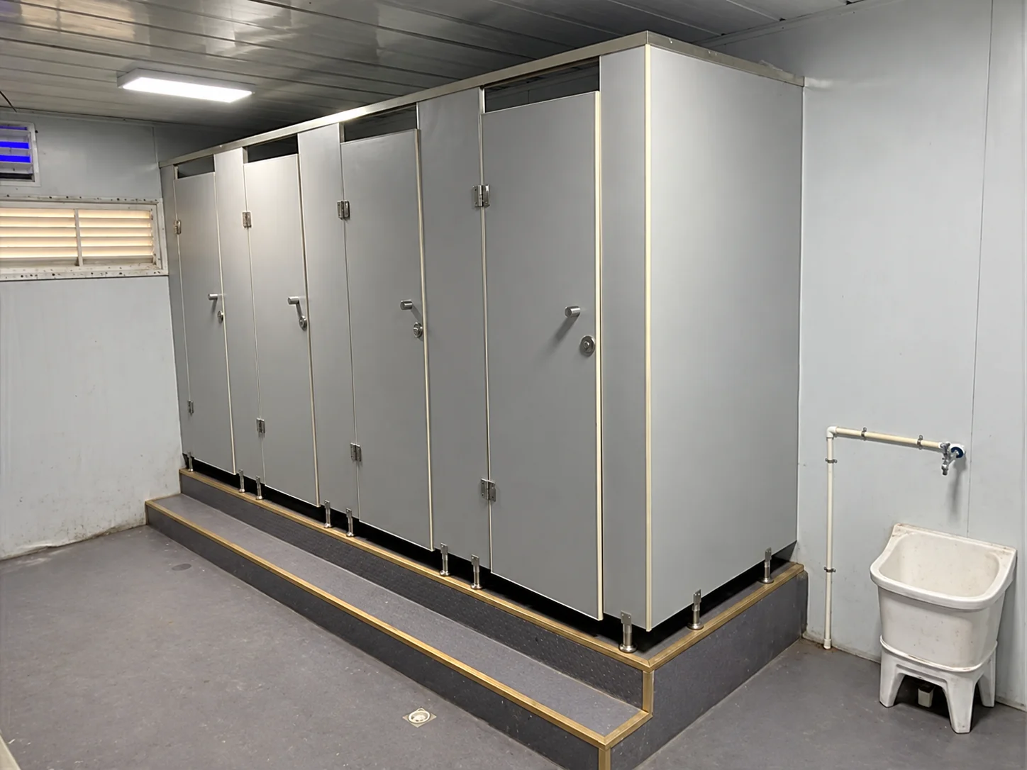 Reference washroom interior with cubicles and a wall-mounted basin