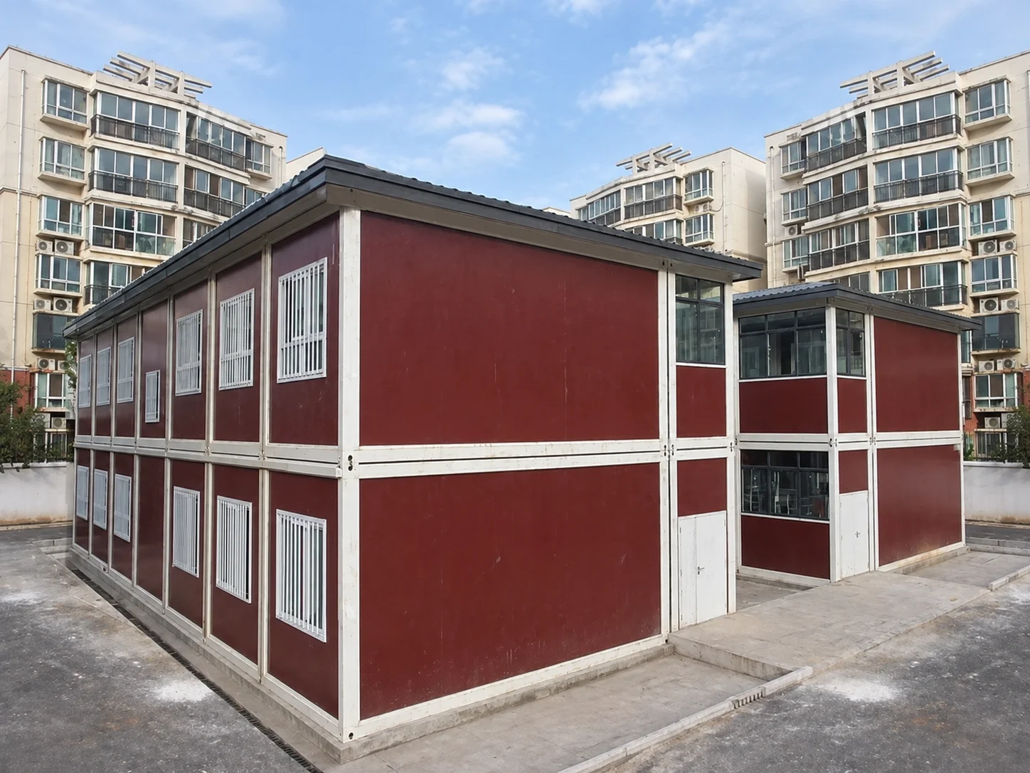 Reference red-and-white two-storey modular building beside apartment blocks