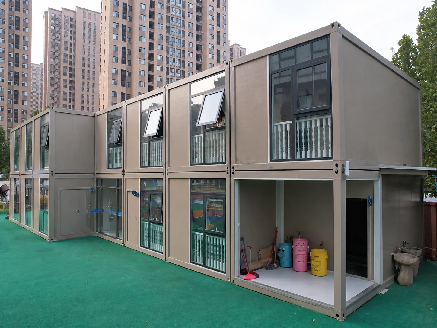 Reference grey stacked modular rooms beside an apartment building