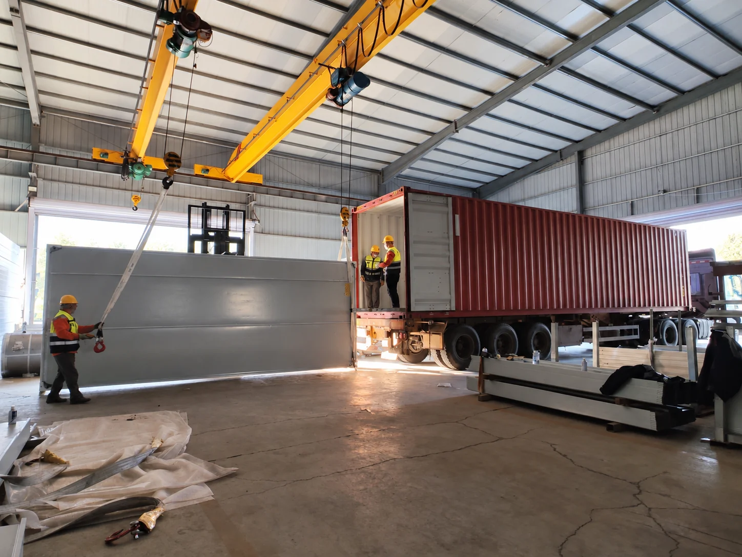 Workshop reference showing lifting equipment beside a shipping container and workers