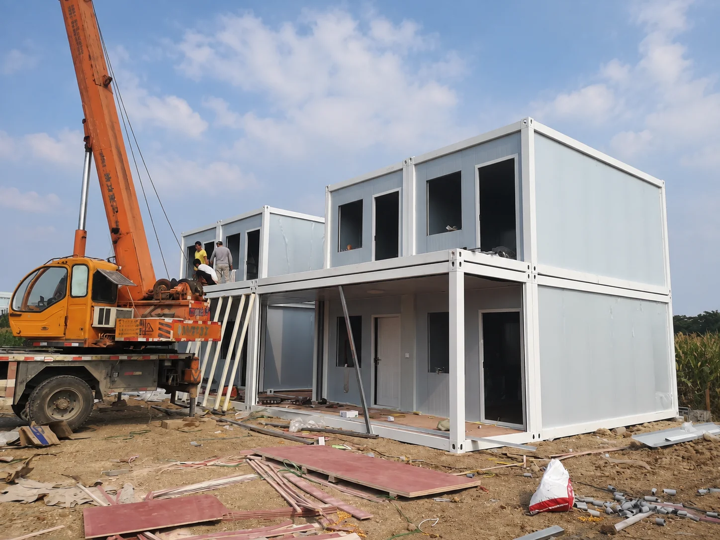 Reference crane beside a two-storey modular building under assembly
