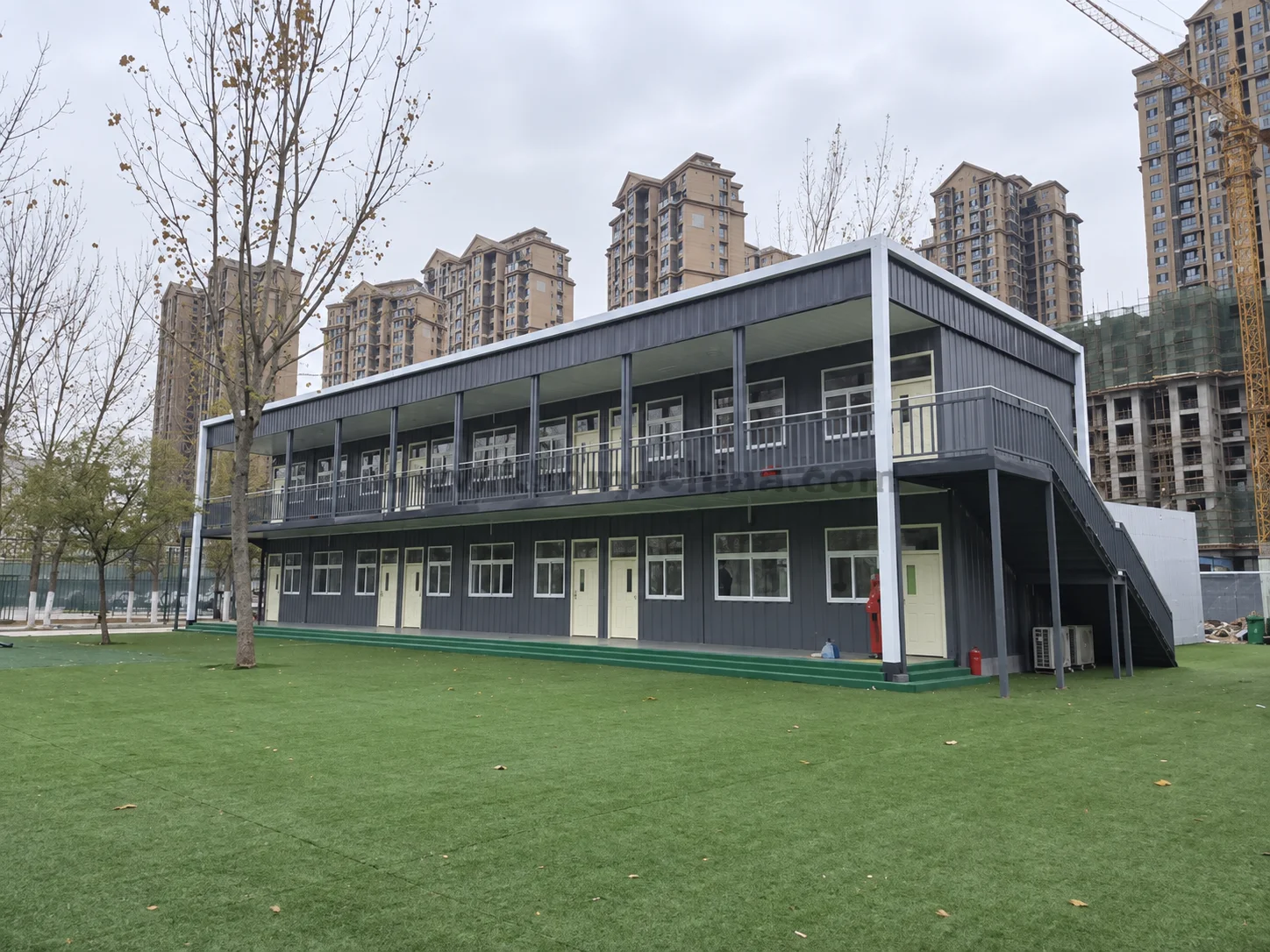 Reference two-storey modular building beside a lawn and apartment blocks