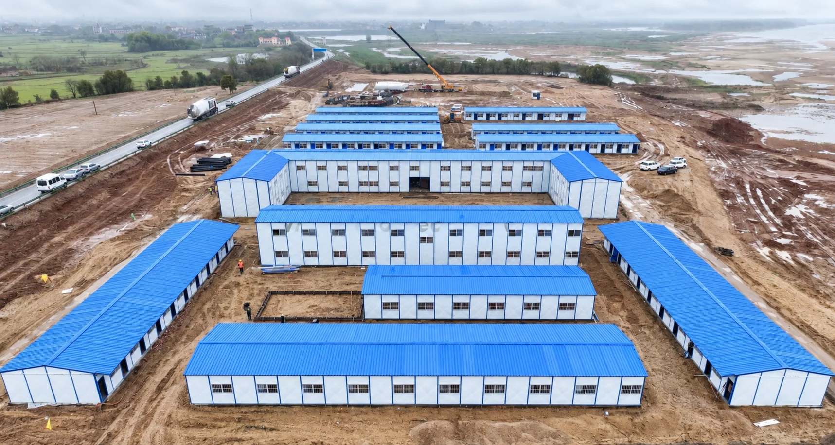 Reference aerial view of long blue-roofed buildings in rows