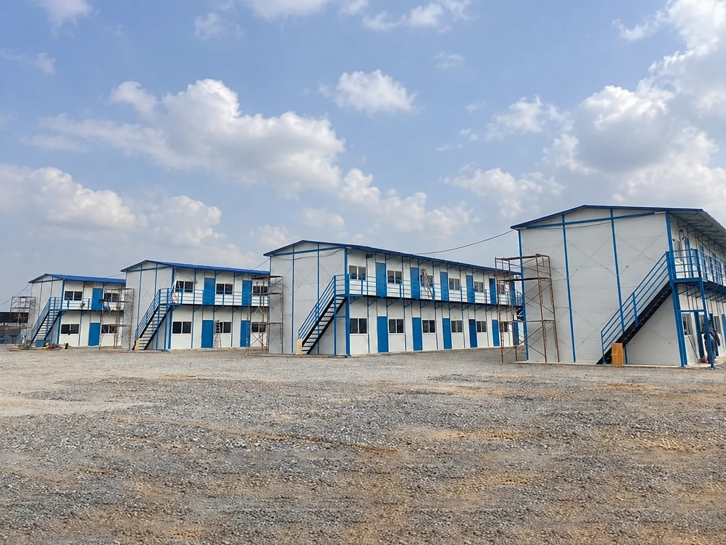 Reference blue-and-white two-storey buildings on a gravel site