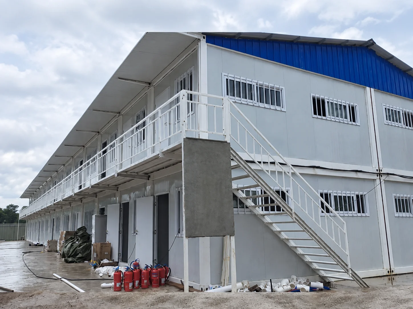 Reference white two-storey modular building with exterior stairs and a blue roof