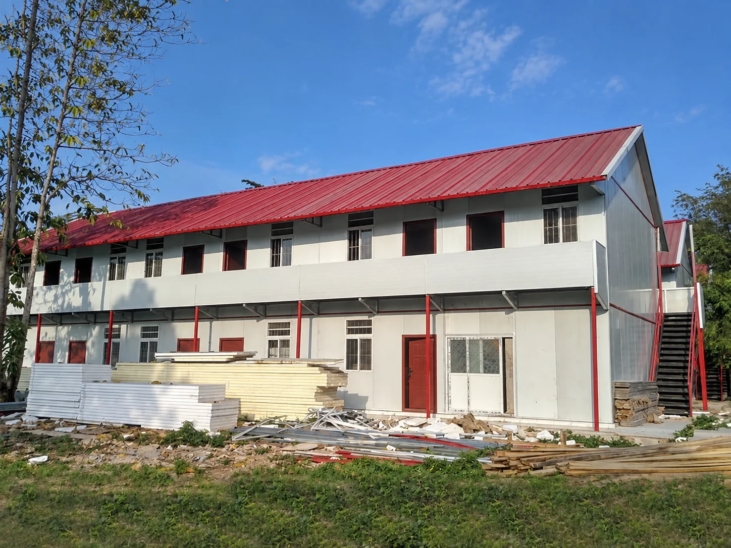 Reference two-storey building with a red roof and exterior walkway