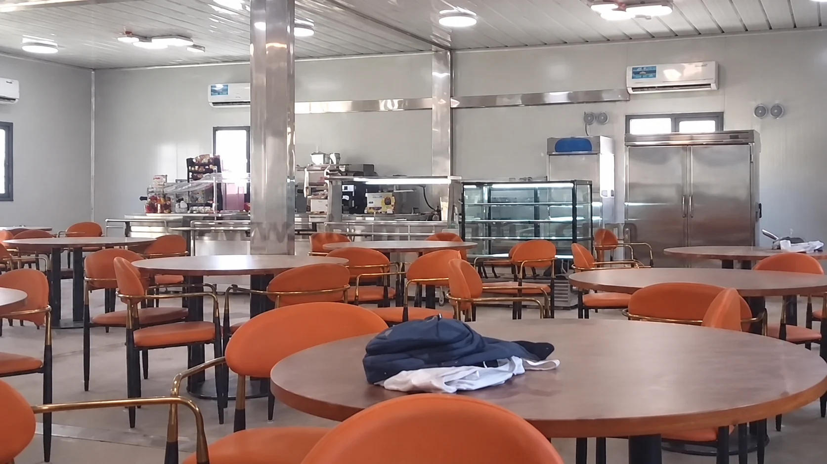 Mesas de comedor redondas y sillas naranjas en el salón modular.