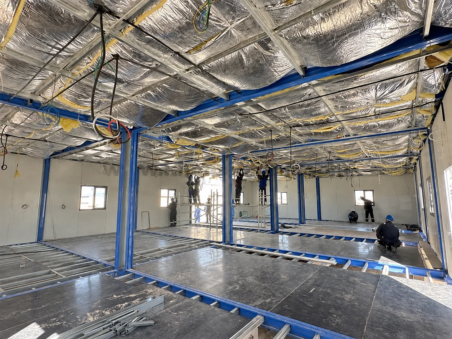 Interior modular amplio con aislamiento y trabajadores durante el acondicionamiento.