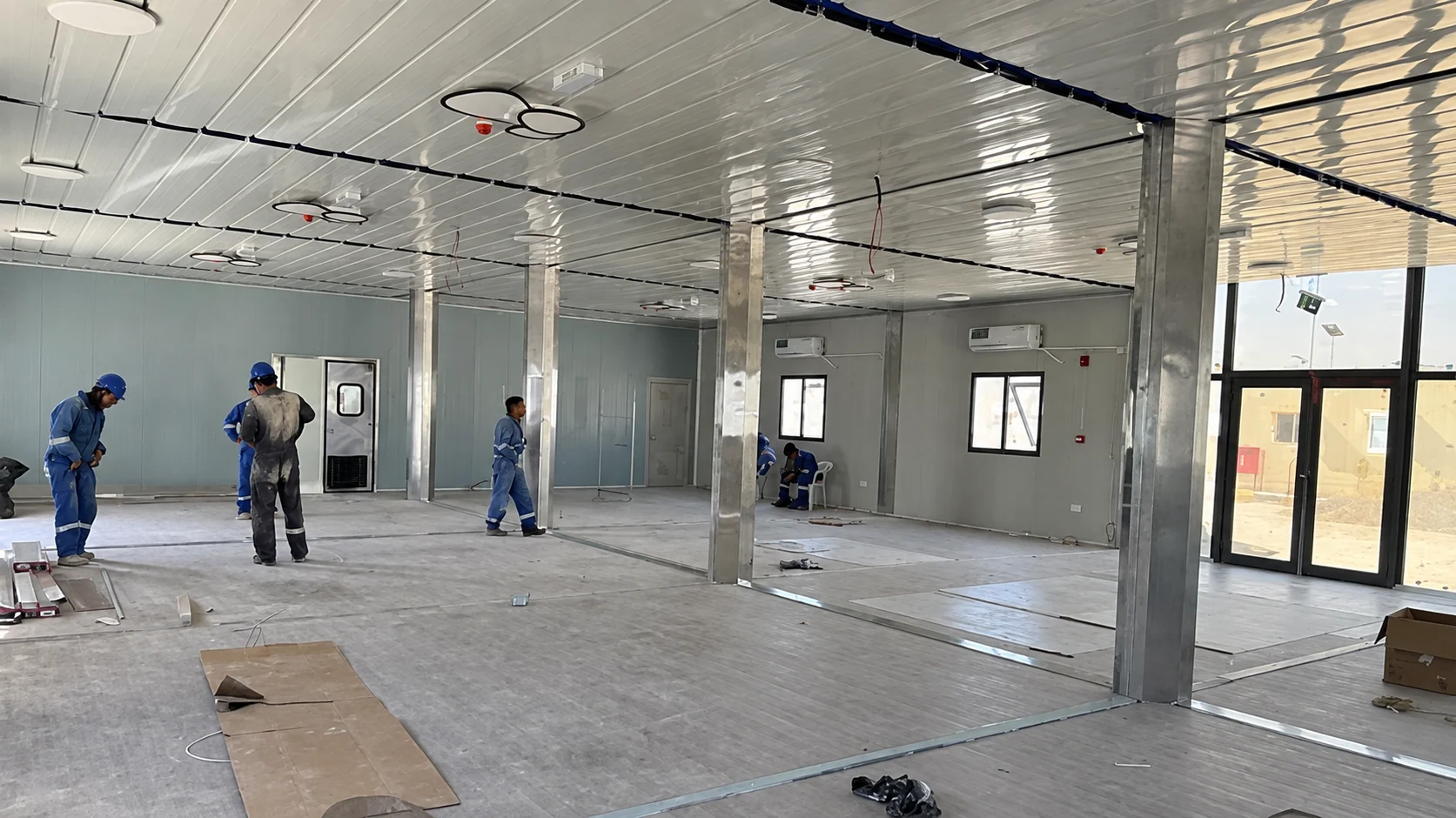 Trabajadores instalando el suelo en el interior del comedor modular.