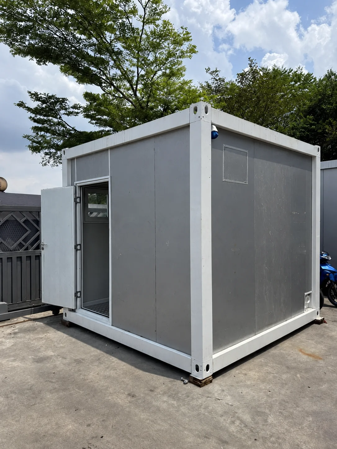 Portfólio de imagens mostrando uma cabine modular compacta cinza com cobertura de entrada.
