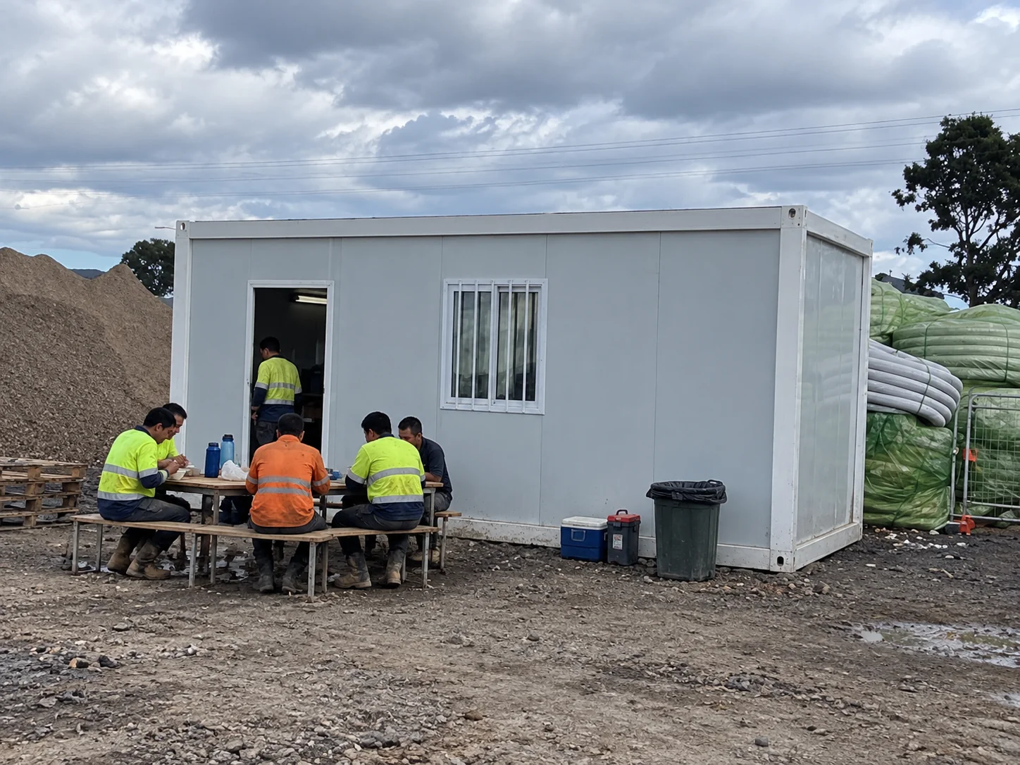 Portfólio de imagens mostrando pessoas sentadas em uma mesa ao ar livre ao lado de uma cabine modular branca.