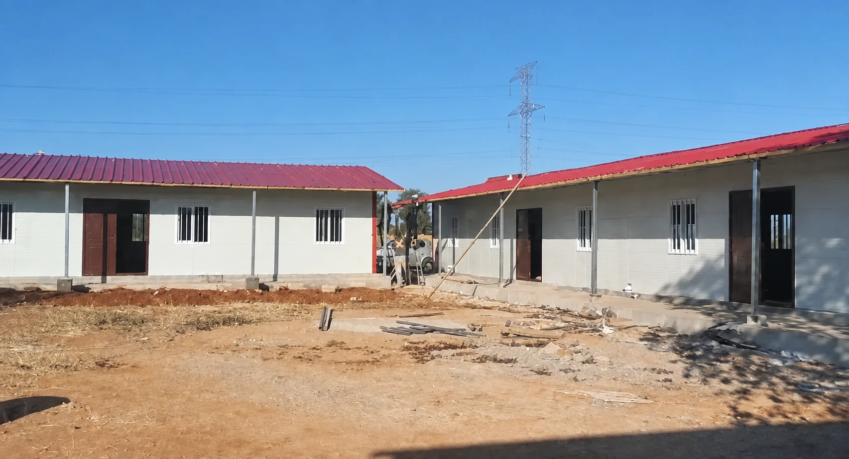 Portfólio de referência mostrando edifícios modulares brancos de um andar com telhados vermelhos ao redor de um pátio aberto.