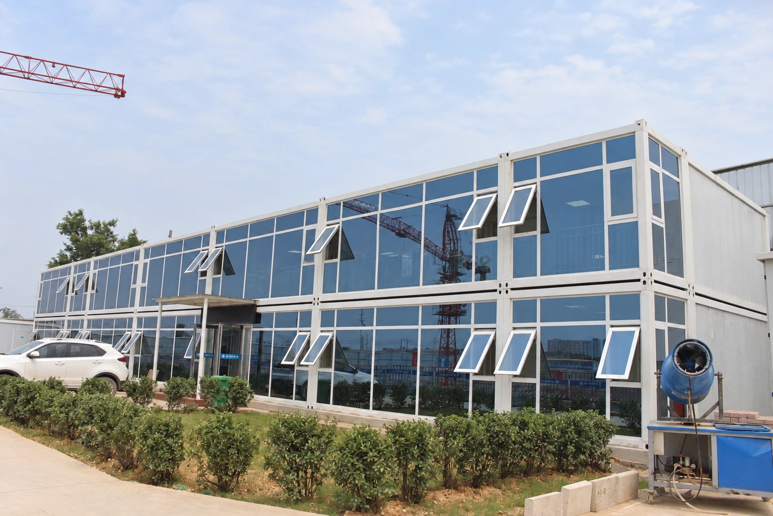 Fotografía exterior de referencia de un edificio modular de dos plantas con amplios ventanales y varias ventanas abatibles.