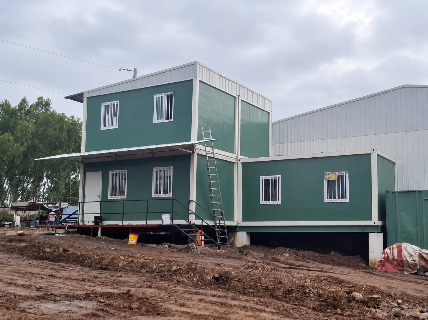 Photographie de référence de blocs modulaires verts disposés en quinconce à deux niveaux, sur un site inachevé.