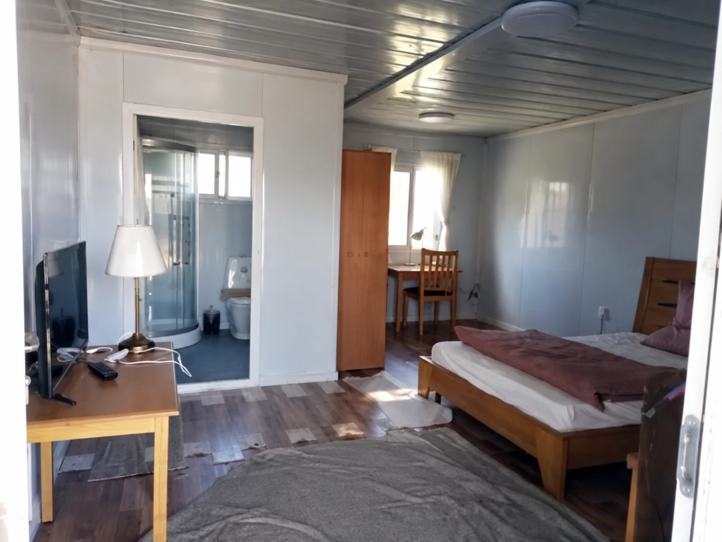 Modular bedroom with a bed, desk and doorway to a washroom; wider room-use reference.
