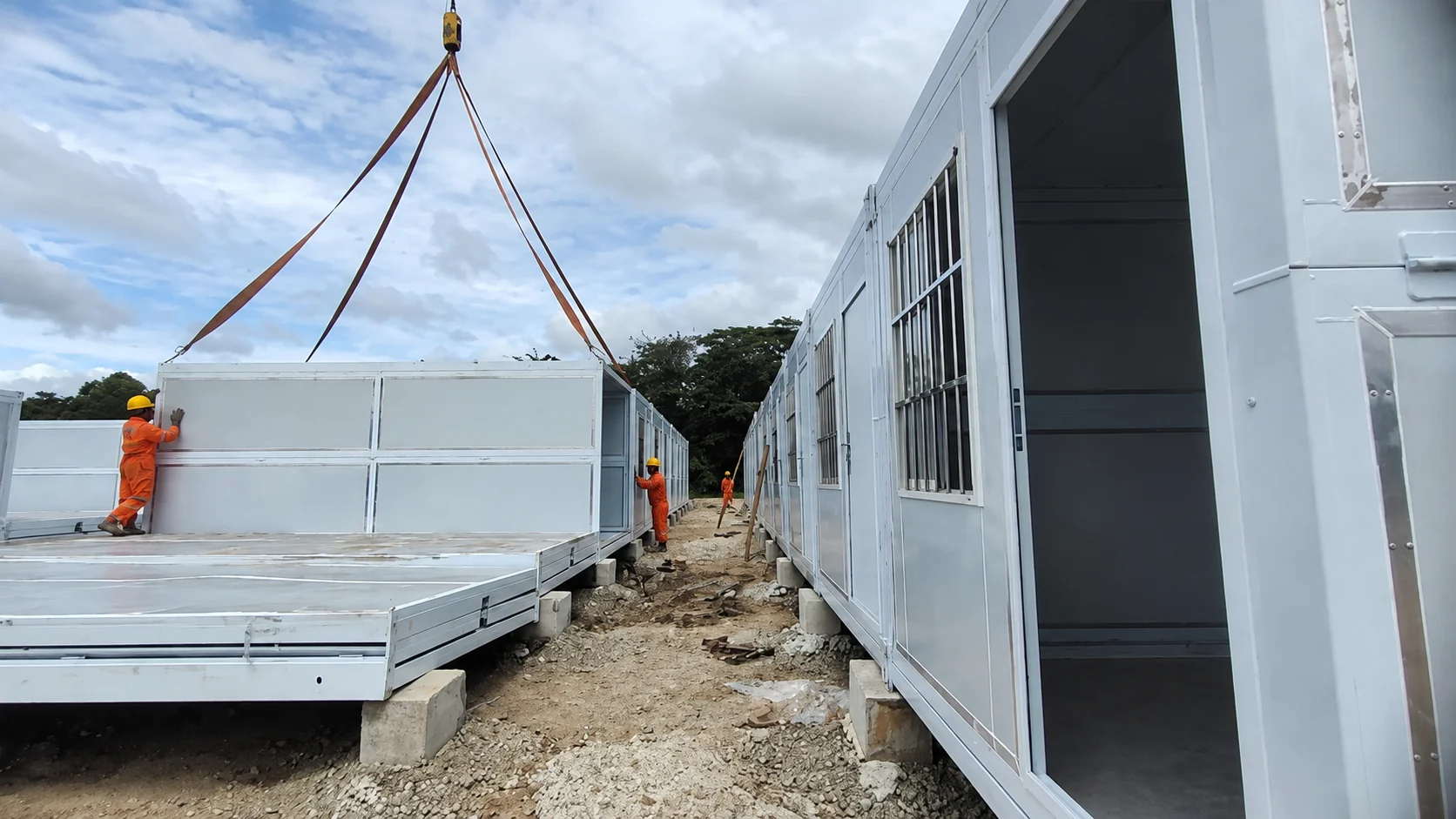 Grue soulevant un module pliable blanc à côté d'une autre unité sur le site du projet aux Philippines