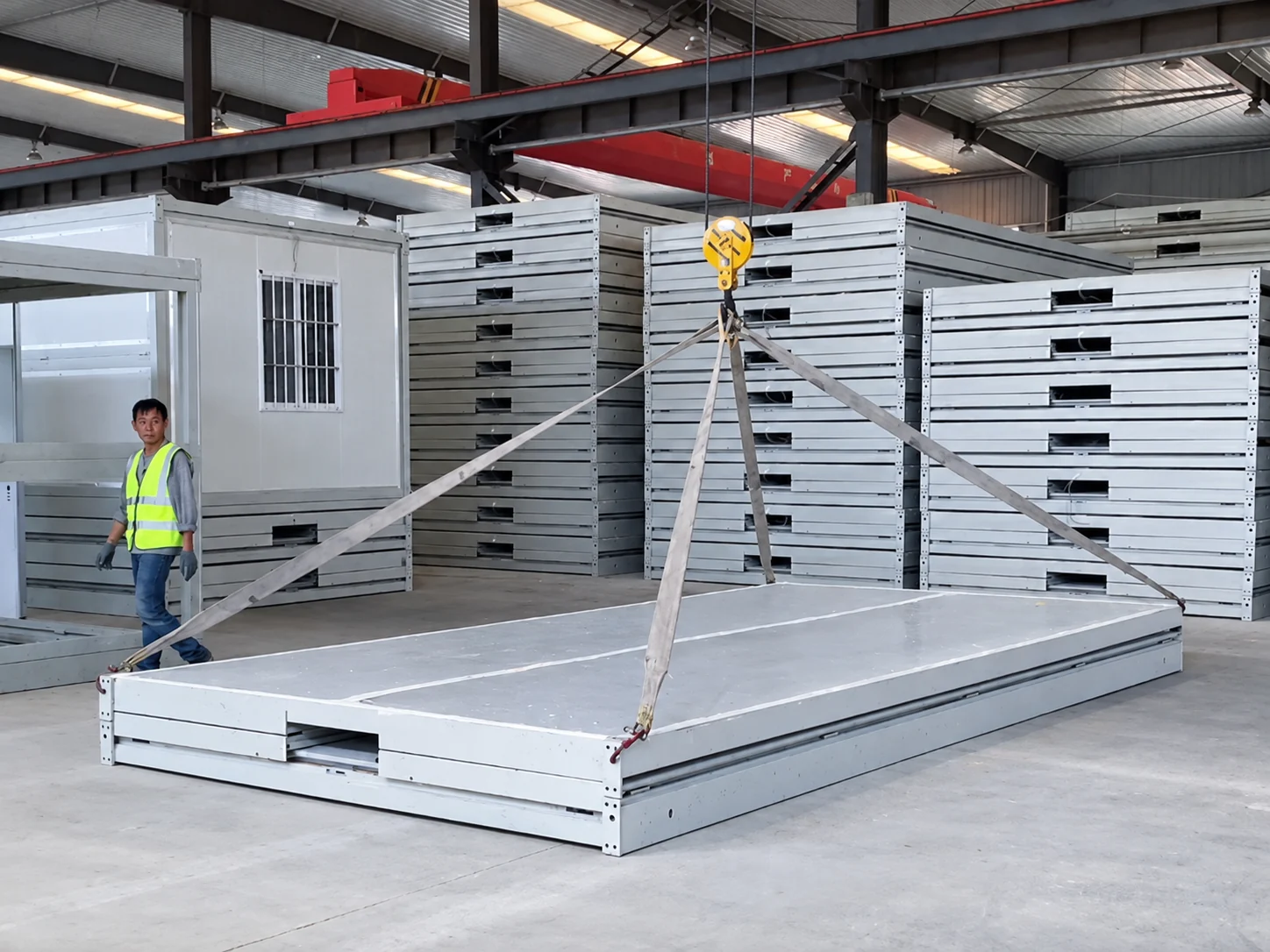 Module de construction plié suspendu à un palan aérien dans un atelier