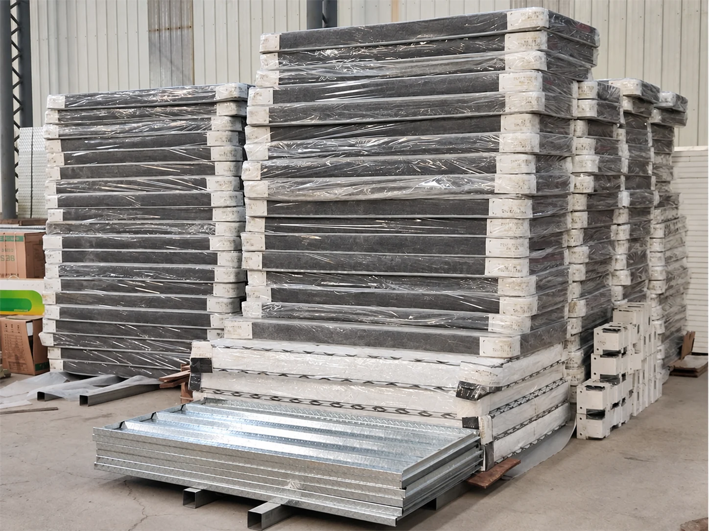 Des piles de panneaux de construction plats sur des palettes dans un atelier