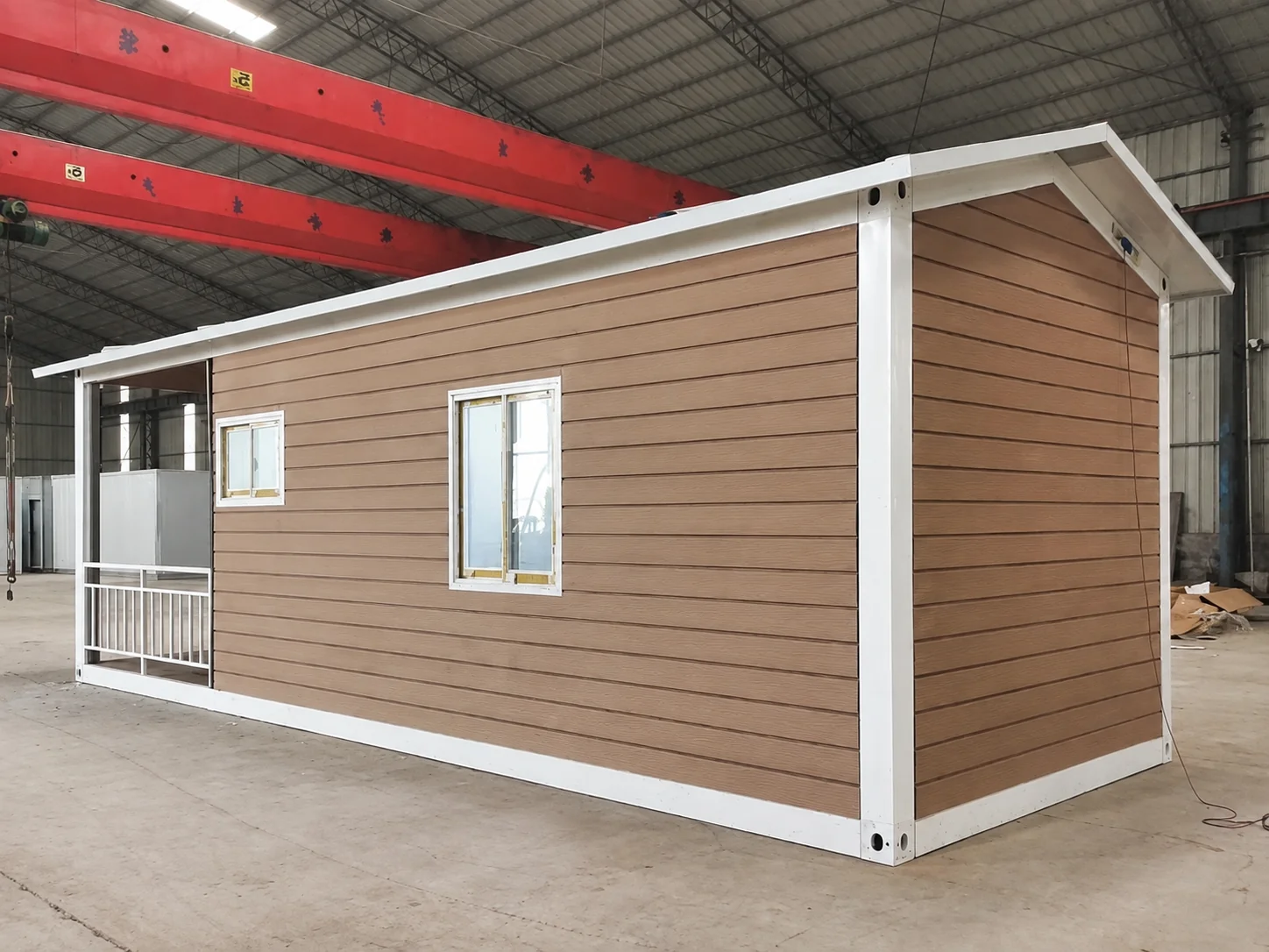 Imagem de referência de oficina mostrando uma cabine modular revestida de marrom sob pontes rolantes.
